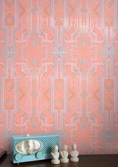 the wallpaper in this room is pink and has an intricate design on it, along with two small statues