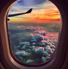 an airplane window with the view of clouds and sunset in the sky as seen from inside