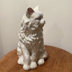 a white cat statue sitting on top of a wooden table