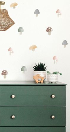 a green dresser sitting next to a wall with mushrooms on it