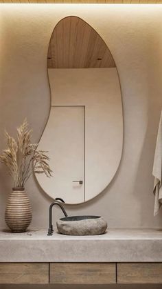 a bathroom sink with a mirror above it and a vase on the counter next to it