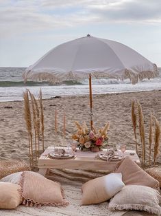 a table set up on the beach with an umbrella