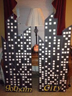 two cardboard city buildings sitting on top of a table next to a lampshade