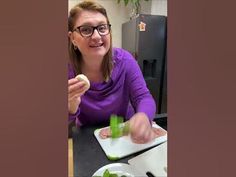 a woman sitting at a table with some food in front of her on a cutting board