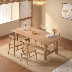 a dining room table with four chairs and a rug on the floor in front of it