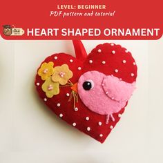 a red heart shaped ornament with a pink bird and yellow flowers on it