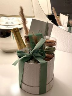 an open gift box filled with cookies and wine bottles sitting on a desk next to a mirror