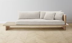 a white couch sitting on top of a hard wood floor next to a wooden table