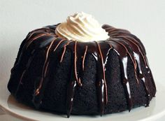 a bundt cake with chocolate icing and whipped cream on top is sitting on a white plate