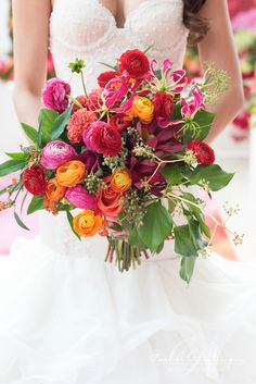 a bride holding a colorful bouquet of flowers in her wedding dress at the end of their ceremony