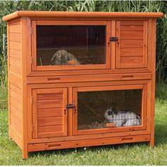 a wooden rabbit hutch with two rabbits in it's cage on the grass