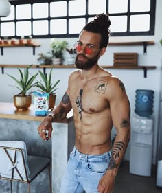 a shirtless man with red glasses standing in front of a table