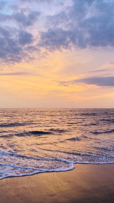 an ocean beach with waves coming in to shore and the sun setting over the horizon