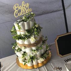 a three tiered wedding cake with flowers and greenery on the top is surrounded by other items