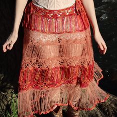 a woman wearing a red skirt standing next to a body of water