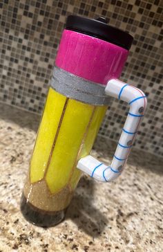 a yellow and pink coffee cup sitting on top of a counter