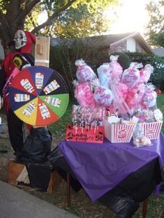 a table topped with candy and decorations next to a man in a red jacket holding an umbrella