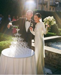 a man and woman standing next to each other in front of a table filled with wine glasses