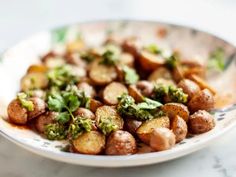 a white bowl filled with potatoes and broccoli on top of a countertop