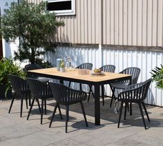 an outdoor table and chairs set up in front of a building with a potted plant next to it