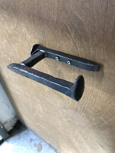 a pair of black handles on a wooden door with holes in the bottom part and an opening to another piece of metal