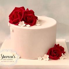 there is a white cake with red roses on it