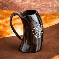 a black pitcher with white snowflakes on it sitting on top of a table