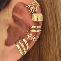 a close up of a person wearing gold ear cuffs