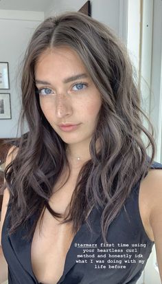 a woman with long dark hair and blue eyes wearing a black top is looking at the camera