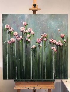 an easel with a painting on it that has pink flowers in the middle and green background