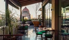 an outdoor restaurant with tables and chairs on the outside patio, overlooking a cityscape