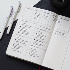 an open notebook on top of a desk next to a pen