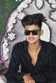 a young man wearing sunglasses sitting on top of a chair