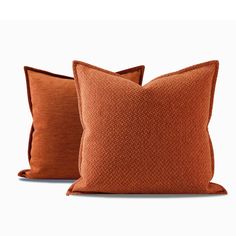 two orange pillows sitting next to each other