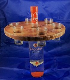 a wooden table with cups on it and a bottle in the middle that says maccorix