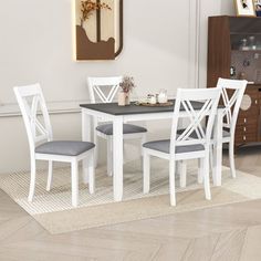 a dining table with four chairs and a rug on the floor in front of it