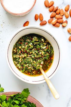 a white bowl filled with pesto and almonds on top of a marble counter