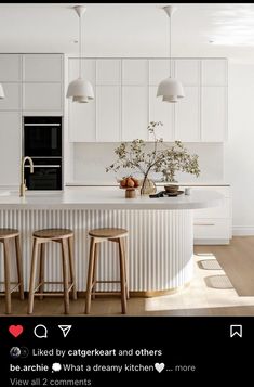 a kitchen with three stools in front of an island and two lights above it