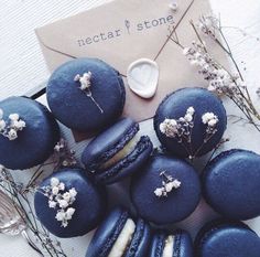 blue macaroons with white flowers on them next to an envelope