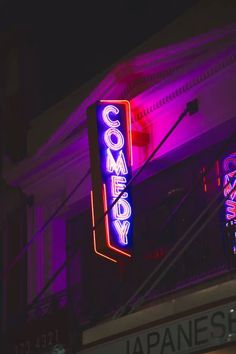 a neon sign that reads comedy on the side of a building