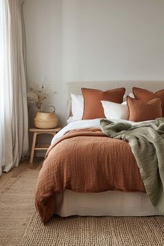 a bed with an orange blanket and pillows