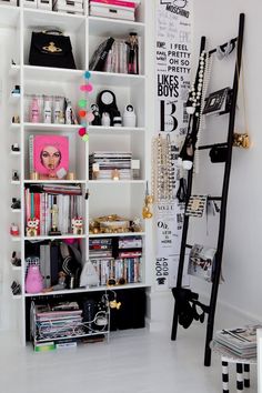 a white bookcase filled with lots of books next to a black and white wall