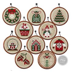 six cross stitch christmas ornaments hanging from hooks