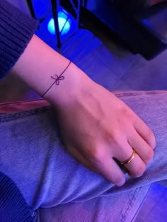 a person's wrist with a small cross tattoo on the left side of their arm