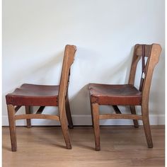 two wooden chairs sitting next to each other on top of a hard wood floored floor