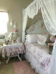 a white bed sitting next to a window covered in curtains and pink flowers on top of it