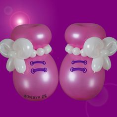 two pink balloons with bows on them are sitting in front of a bright purple background