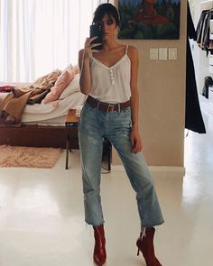 a woman is taking a selfie in her bedroom while wearing high heeled boots