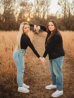 two young women standing in a field holding hands