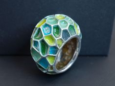 A gorgeous enameled ring in a size 7 1/2. Featuring a beautiful selection of blue and green enamel colors with a lovely emerald hidden on the back of the ring for the wearer to admire. This sculptural ring wears very comfortably and will bring a splash of bright color and joy to any day; sure to pair well with any outfit. Materials: Glass Enamel, Natural Emerald, Sterling Silver Green Enamel Round Ring, Modern Green Round Dome Ring, Green Enamel Rings As A Gift, Unique Blue Enamel Ring, Green Handmade Fusion Rings, Unique Green Open Ring, Unique Green Enamel Ring For Gift, Modern Green Enamel Jewelry, Unique Green Open Ring Jewelry